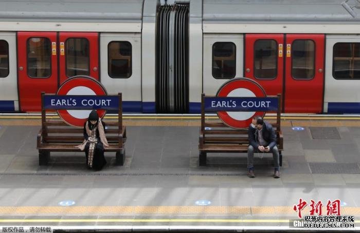 资料图：英国“有条件解封”，出行的伦敦市民坐在伯爵法院站的长凳上。